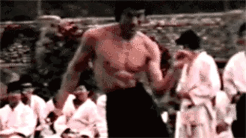 Shirtless Man Standing In Front Of Group GIF