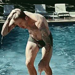 Shirtless Man Standing in Pool With Hand on Head