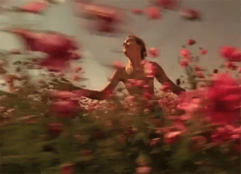 Shirtless Man Standing In Red Flowers Arms Outstretched GIF