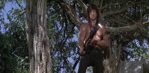 Shirtless Man Standing in Tree With Sword