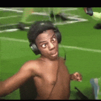 Shirtless Man Wearing Headphones Taking Selfie on Field