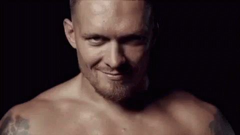 Shirtless Man with Beard Smiling in Dark Room