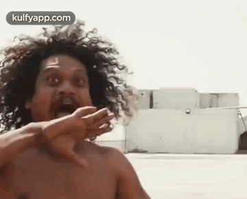 Shirtless Man With Curly Hair Funny Face In Front Of Building GIF