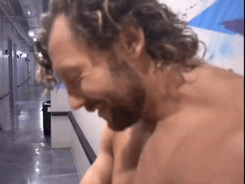 Shirtless Man With Curly Hair Sitting in Hallway
