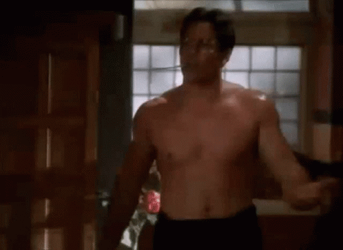 Shirtless Man With Glasses Standing In Front Of Window GIF