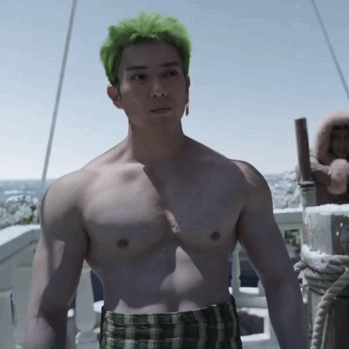 Shirtless Man With Green Hair and Plaid Shorts on Balcony