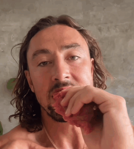 Shirtless Man With Long Hair Eating Meat GIF