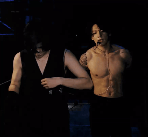 Shirtless Man With Microphone Next to Another Man