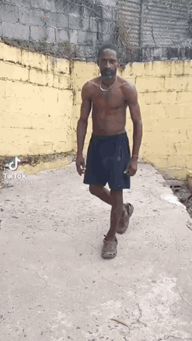 Shirtless Man With Mustache And Necklace Walking Down Sidewalk GIF