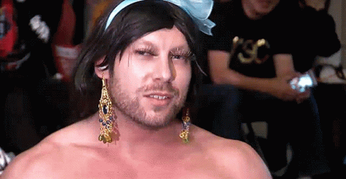 Shirtless Man With Wig Earrings and Bow