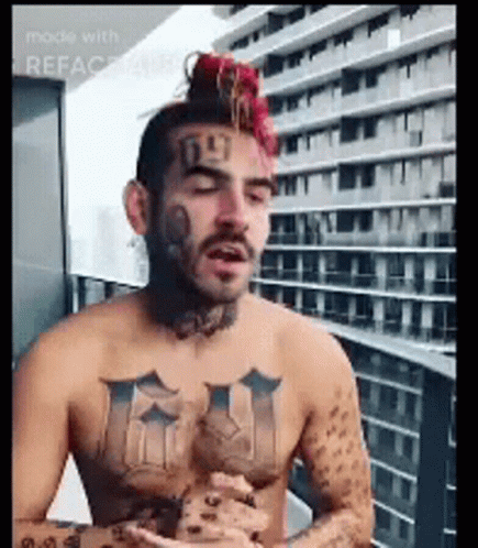 Shirtless Tattooed Man Sitting On Balcony GIF