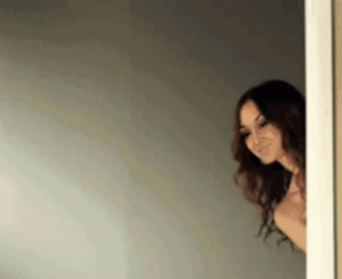 Shirtless Woman Peeking From Doorway Smiling GIF