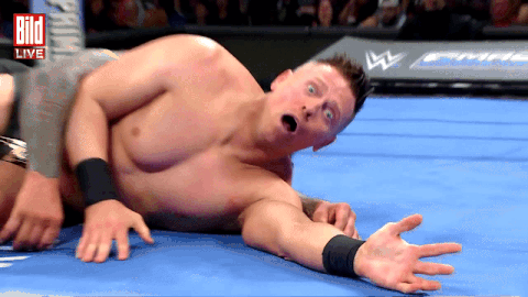 Shirtless Wrestler Lying in Front of Live Sign