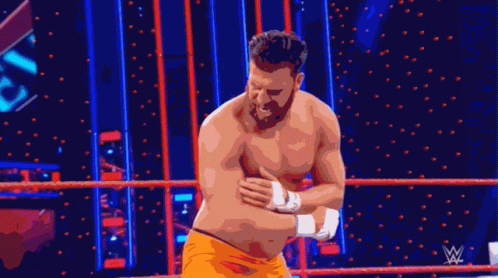Shirtless Wrestler Standing in Ring With Wrestling Logo