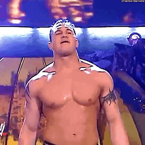Shirtless Wrestler With Bandage on Head Standing in Room
