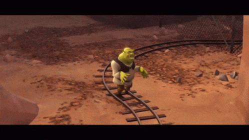 Shrek Is Walking On Train Tracks In A Desert GIF