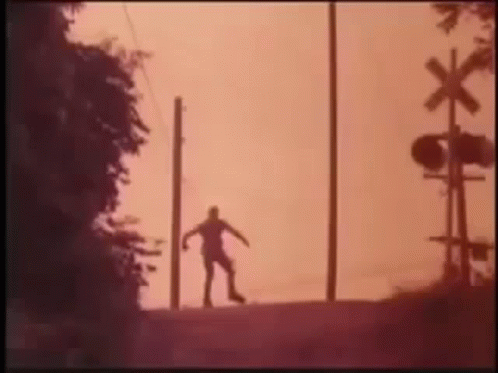 Silhouette of Person at Railroad Crossing Sunset
