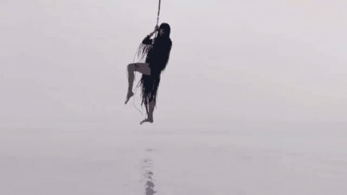 Silhouette of Woman Hanging from Rope in Sky