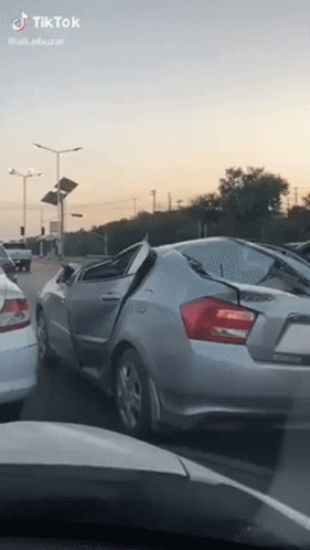 Silver Car With Broken Windshield Driving on Street