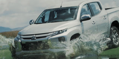 Silver Mitsubishi Truck Driving Through Puddle