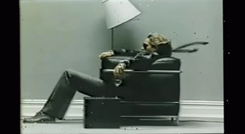 Skeleton Sitting In Chair With Lamp On Head GIF