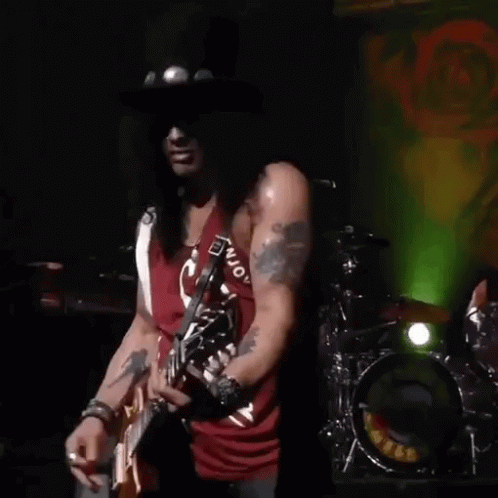slash of guns n ' roses is playing a guitar on stage .