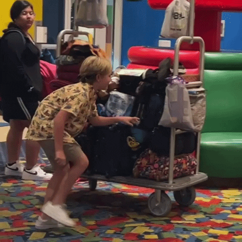 Sly Young Boy Hiding Behind Luggage GIF