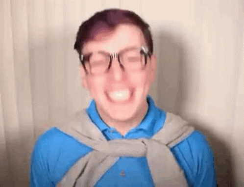 Smiling Man in Glasses, Blue Shirt, and Gray Sweater