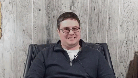 Smiling Man in Glasses Sitting in Chair
