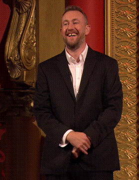 Smiling Man in Suit Before Gold Wall