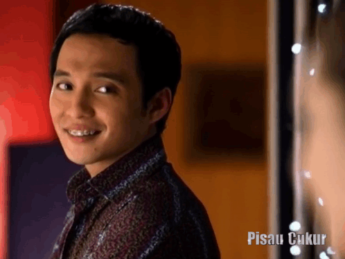 Smiling Man with Braces in Front of Pisau Cukup Sign