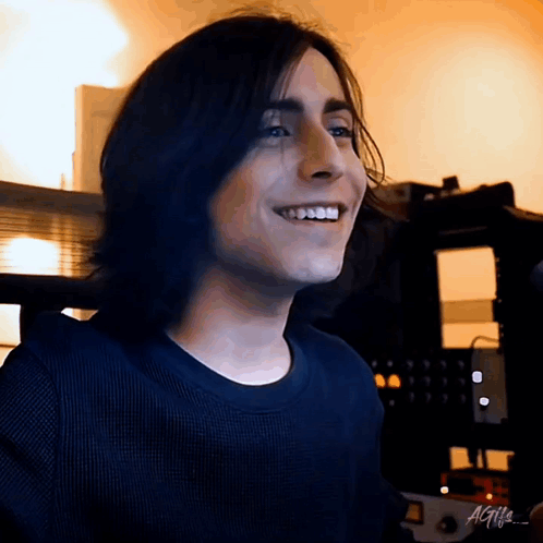 Smiling Young Man With Long Hair and Black Shirt
