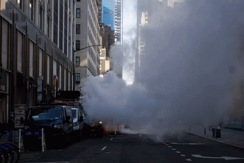 Smoke Is Coming Out Of A Drain On The Side Of The Road GIF