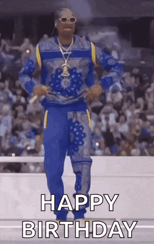 Snoop Dogg Is Dancing In Front Of A Crowd While Wearing A Blue And Yellow Outfit . GIF