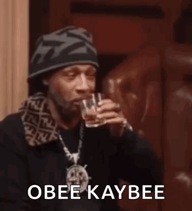 Snoop Dogg Is Drinking From A Glass While Wearing A Hat . GIF