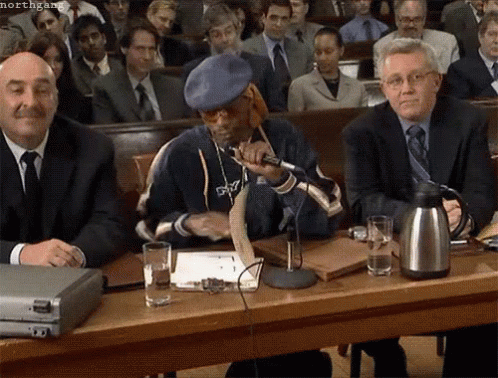 Snoop Dogg Is Sitting At A Table With A Microphone In Front Of A Crowd Of People GIF