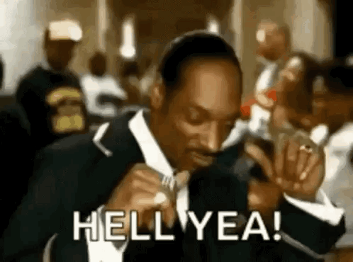 Snoop Dogg Is Wearing A Suit And Tie And Smoking A Cigarette In A Crowd . GIF