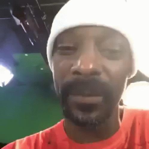 Snoop Dogg Is Wearing A White Hat And An Orange Shirt While Making A Funny Face . GIF
