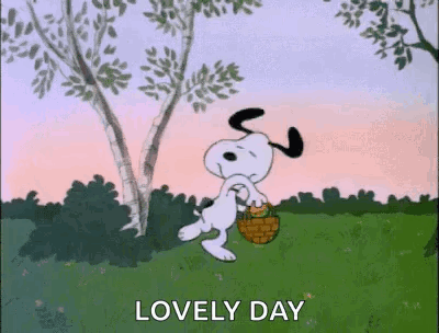 Snoopy Is Walking In A Field With A Basket And A Tree In The Background . GIF
