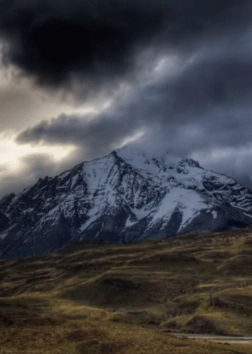 Snow-Covered Mountain Under Dark Cloudy Sky