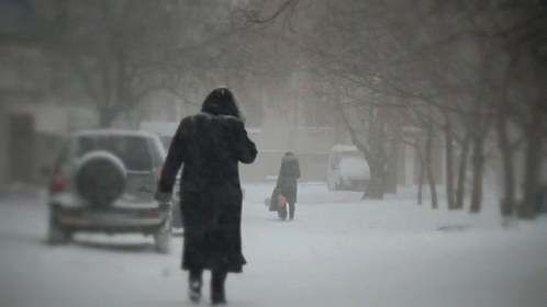 Lady In Trench Coat Walking In Snow Storm GIF