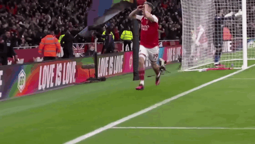 Soccer Player Celebrating Goal with Love Is Love Banner