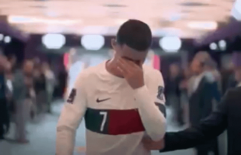 Soccer Player Facepalms, Man in Suit Holds Shoulder