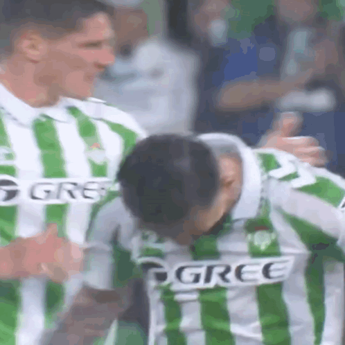 Soccer Player in Green and White Striped Jersey Being Hugged