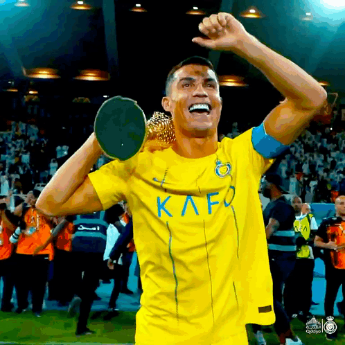 Soccer Player in Yellow Kafo Jersey Holding Trophy Over Head