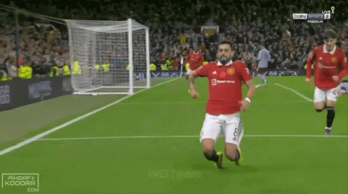 Soccer Player Kneeling While Another Runs Toward Him GIF