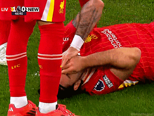 Soccer Player Laying on Ground Being Helped Up