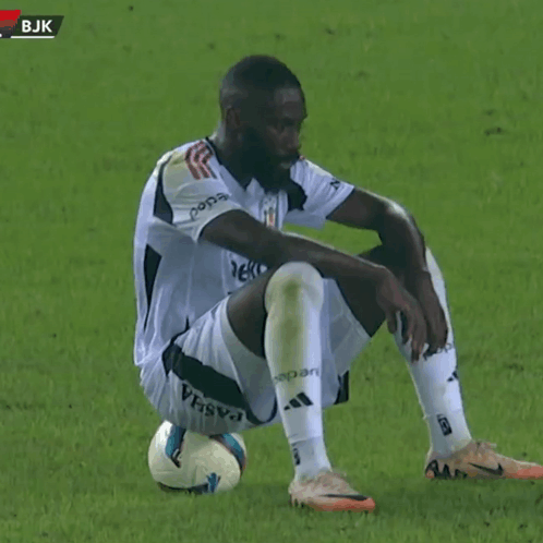 Soccer Player Sitting with Knee on Ball