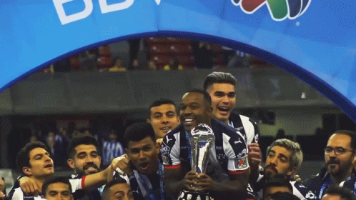 Soccer Players Celebrate With Trophy In Front Of BB Banner