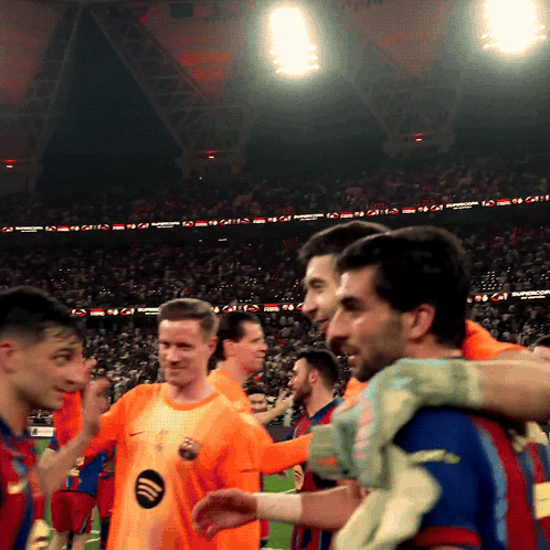 Soccer Players Huddled in Stadium with Spotify Logo